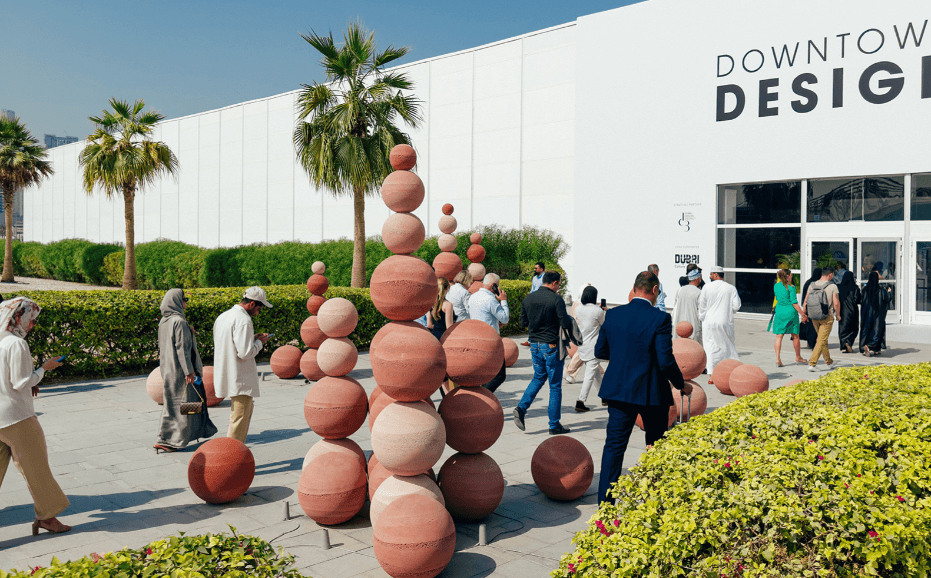 Visitors walk past towers of stacked terracotta spheres outside the Downtown Design exhibition building. - Image 1 of 1